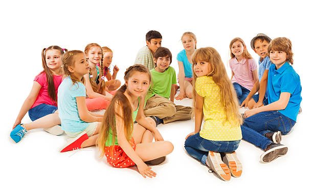 Little beautiful boy sit in the center of circle of large group of kids